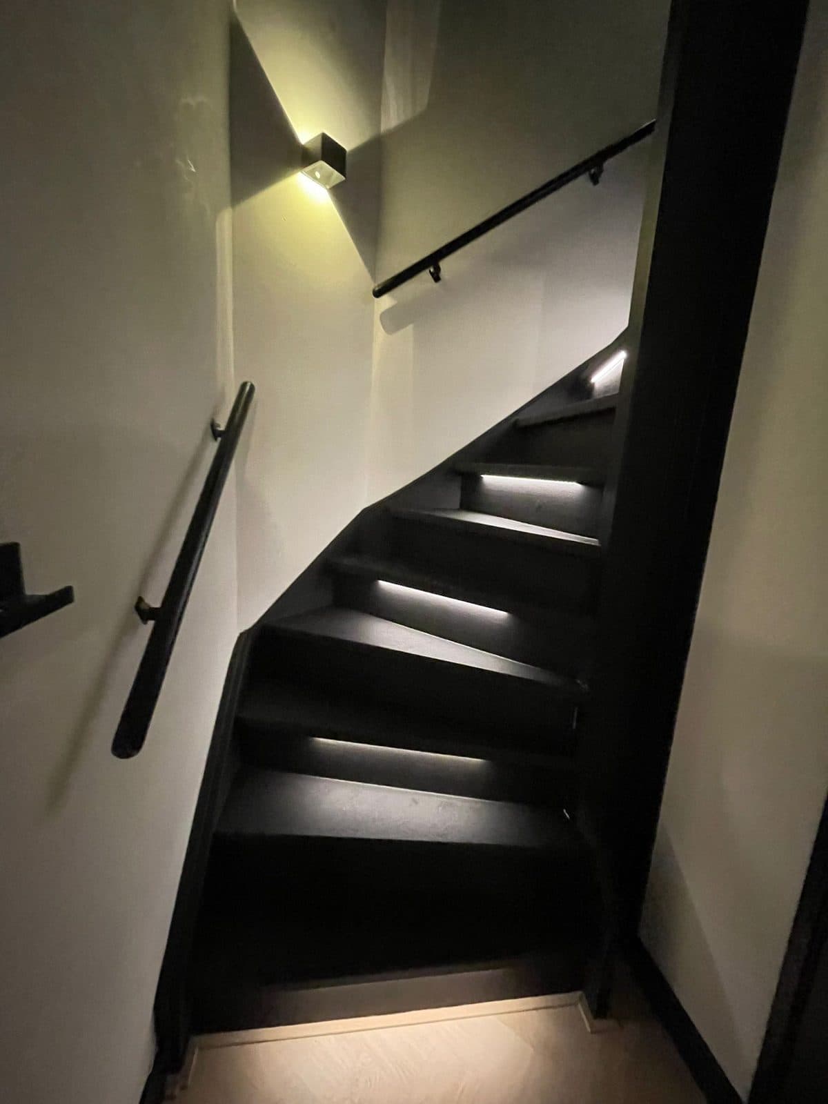 Dichte trap met Signature-afwerking in een donkere tint en geïntegreerde LED-verlichting onder de trapneuzen.