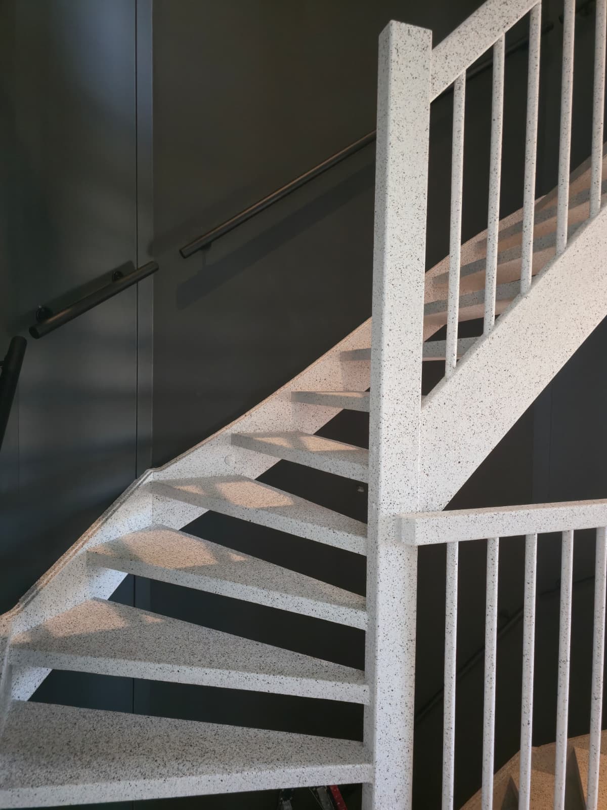Signature traprenovatie — open trap in wit terrazzo tegen donkere wand